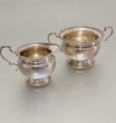 A Birmingham silver two handled sugar basin and creamier with gadroon borders and c scroll