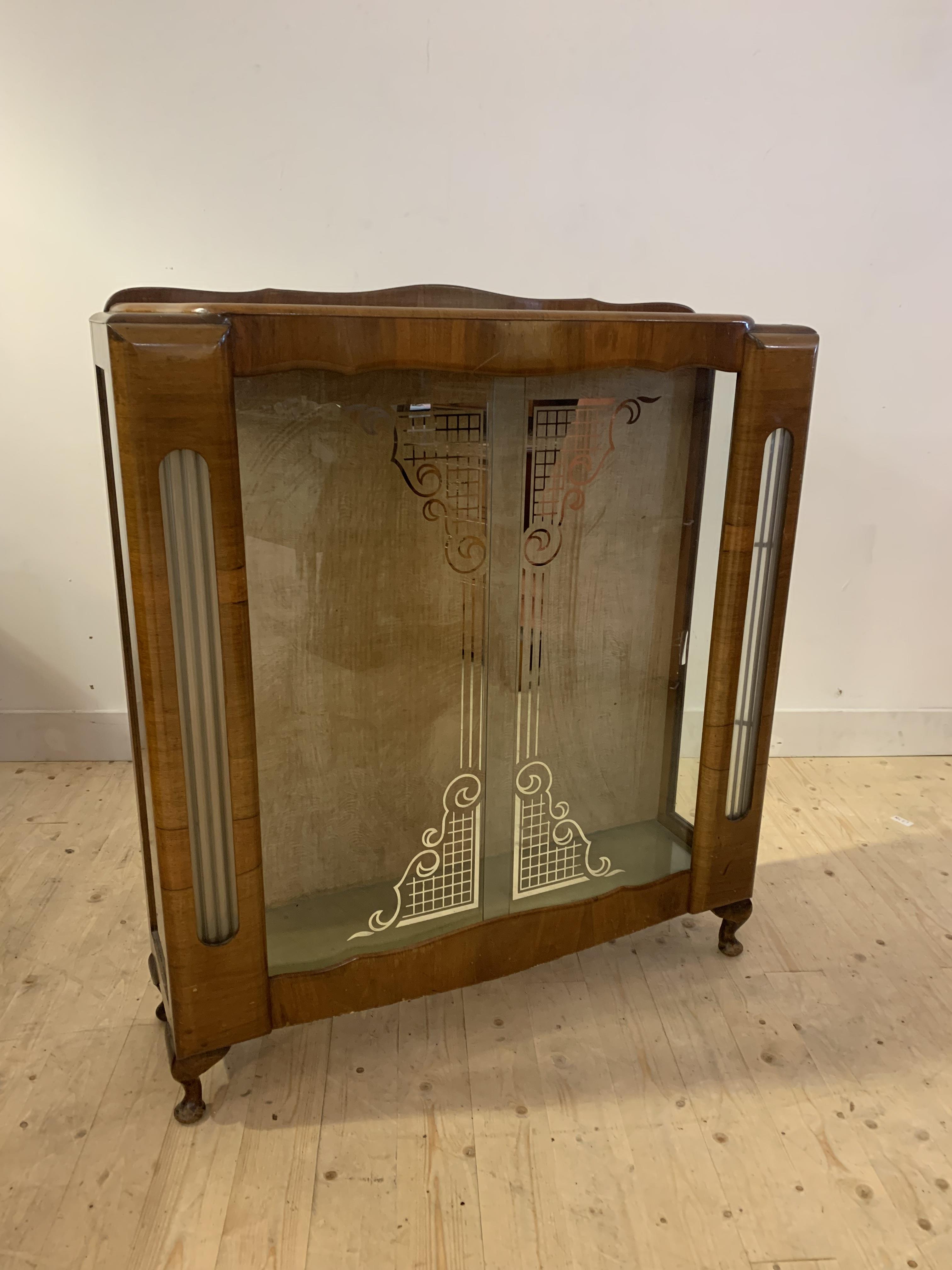 An Art Deco period walnut vennered display cabinet, with sliding glass doors enclosing two