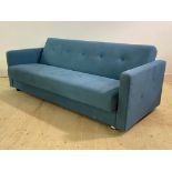 A Mid century modern metamorphic sofa bed, upholstered in a buttoned blue fabric, the back rest