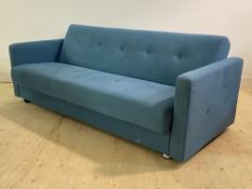 A Mid century modern metamorphic sofa bed, upholstered in a buttoned blue fabric, the back rest