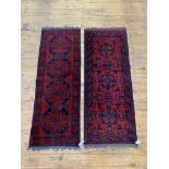 A matched pair of hand knotted Afghani runner rugs of typical palette and design, 155cm x 66cm