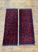 A matched pair of hand knotted Afghani runner rugs of typical palette and design, 155cm x 66cm