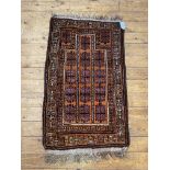 A hand knotted baluchi prayer rug, the madder field with geometric mihrab and bordered, 1230cm x