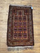 A hand knotted baluchi prayer rug, the madder field with geometric mihrab and bordered, 1230cm x