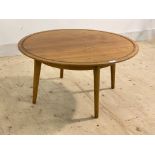 A mid century vintage teak and walnut coffee table, the circular top with incised border raised on