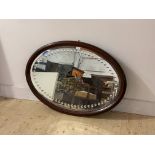 An Edwardian mahogany framed oval wall mirror, with bevelled and incised plate, 102cm x 71cm
