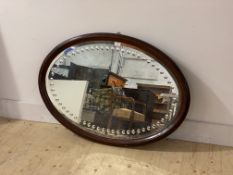 An Edwardian mahogany framed oval wall mirror, with bevelled and incised plate, 102cm x 71cm