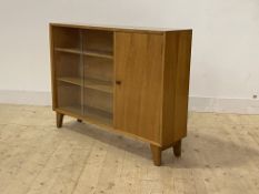 A mid century teak bookcase, with twin sliding doors enclosing two adjustable shelves, flanked by