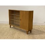 A mid century teak bookcase, with twin sliding doors enclosing two adjustable shelves, flanked by