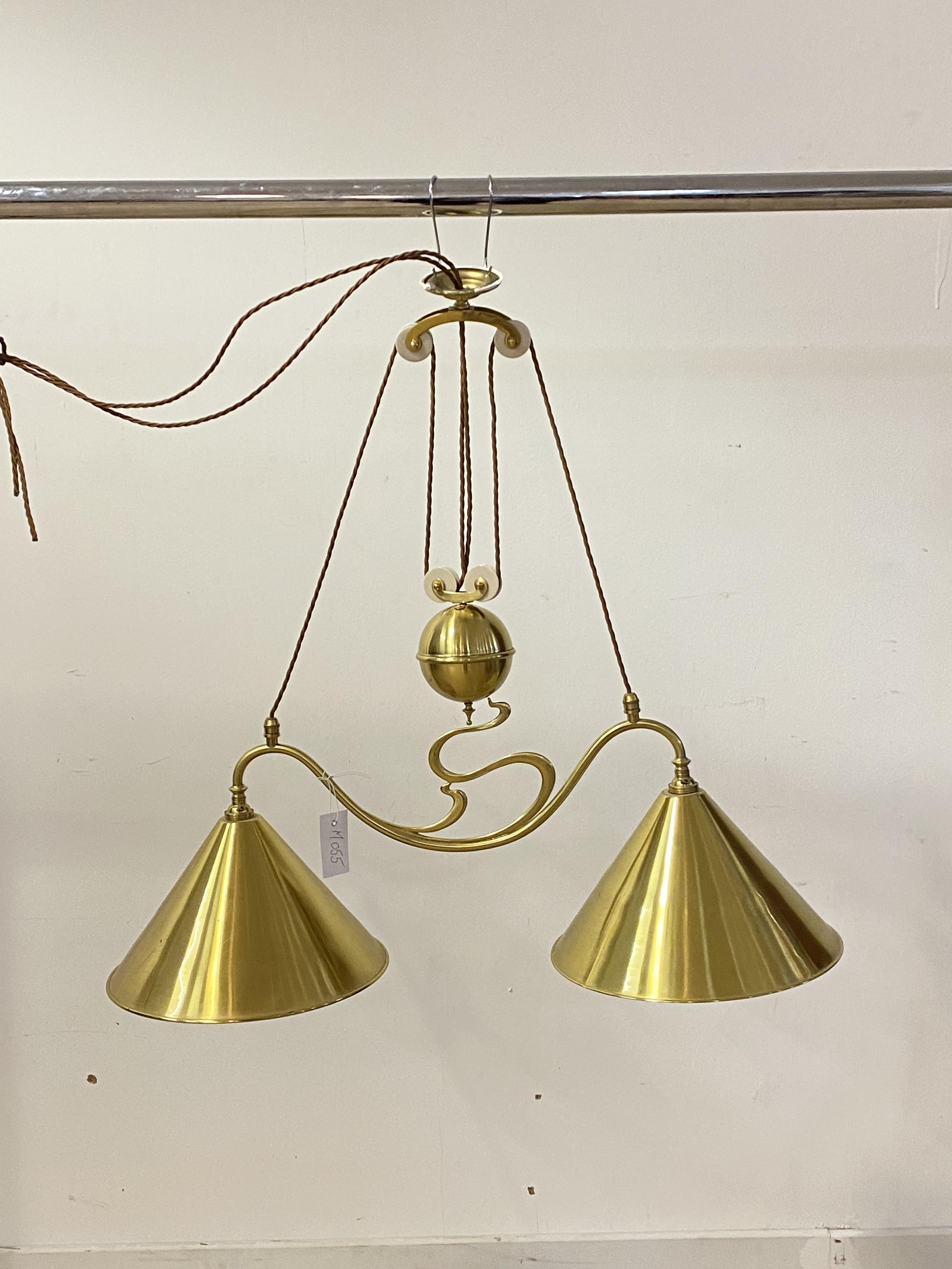 A brass Art Nouveau design rise and fall ceiling light fitting, with two conical shades, W80cm