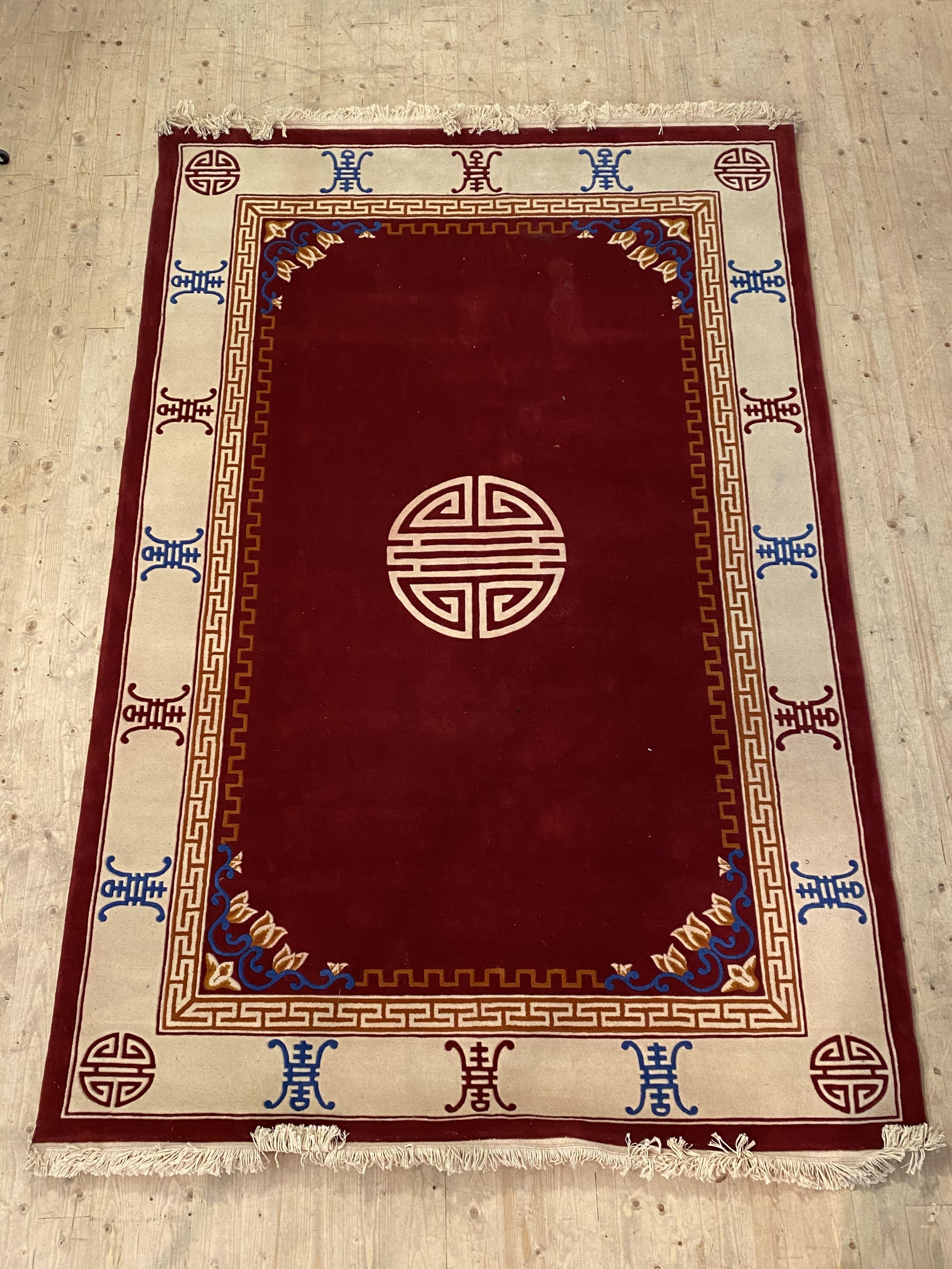 A Chinese washed wool rug, the red field enclosed by an ivory border, 200cm x 310cm
