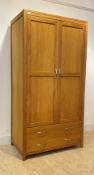 A contemporary light oak wardrobe, the double doors with hanging rail behind, over two long drawers,
