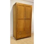 A contemporary light oak wardrobe, the double doors with hanging rail behind, over two long drawers,