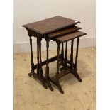 An early 20th century walnut nest of three tables, raised on ring turned and sledge supports, H57cm,