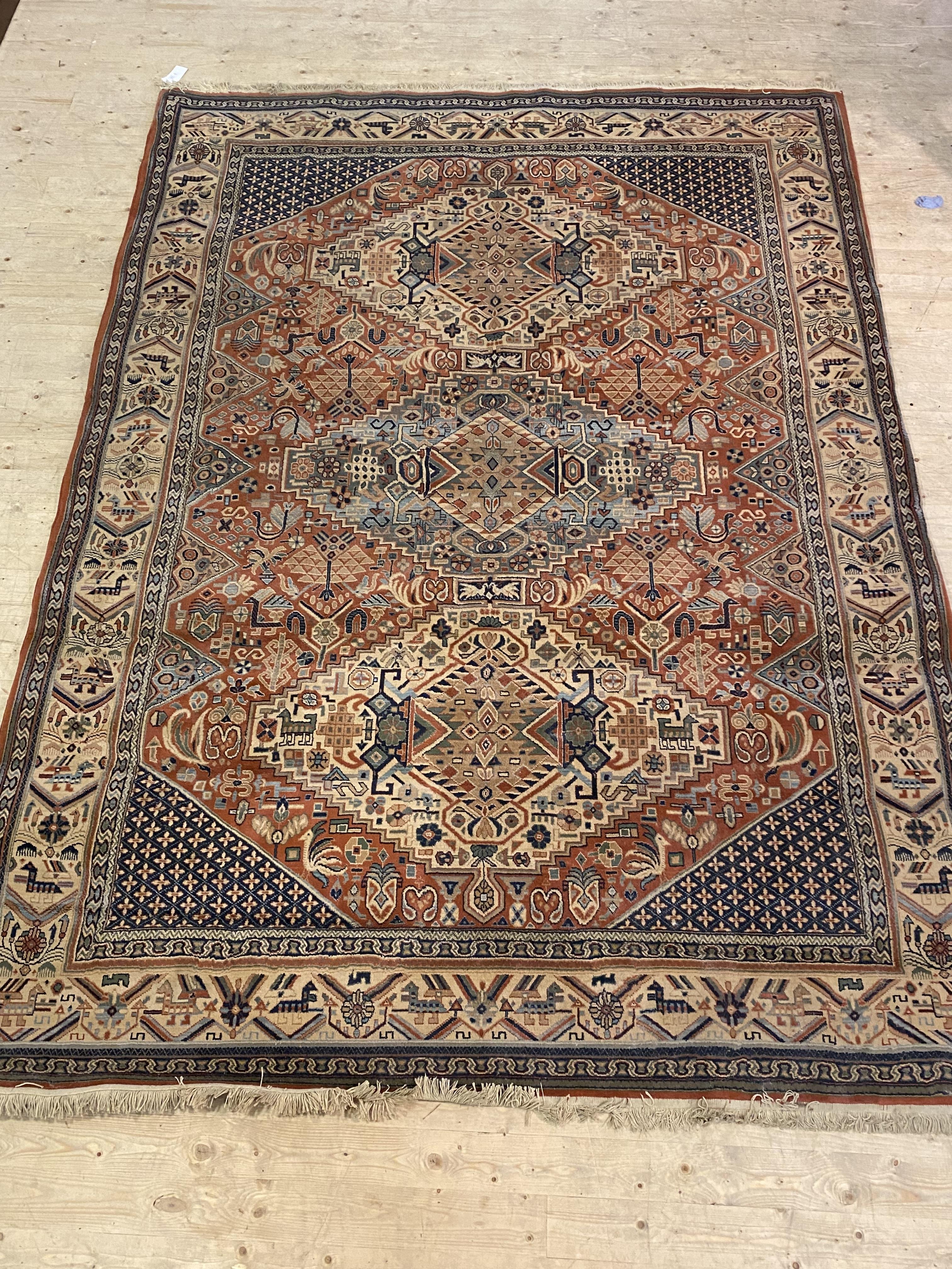 A Persian design Shiraz rug, the busy red field decorated with stylised floral and animal motifs,