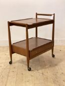 A mid century teak drinks trolley, the lift of tray top over drawer to base, raised on turned