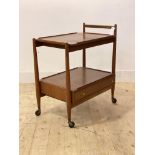 A mid century teak drinks trolley, the lift of tray top over drawer to base, raised on turned