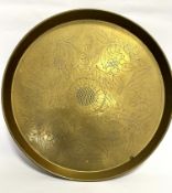 An Eastern inspired circular brass tray with centre flowerhead enclosed within a scrolling leaf