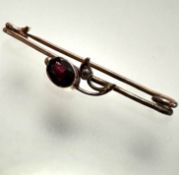 An Edwardian yellow metal bar brooch mounted oval faceted garnet with rose cut diamond set leaf,