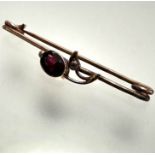 An Edwardian yellow metal bar brooch mounted oval faceted garnet with rose cut diamond set leaf,