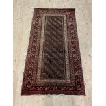 A Persian hand knotted rug, the brown field enclosed by a multi line border 191cm x 99cm