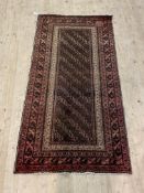 A Persian hand knotted rug, the brown field enclosed by a multi line border 191cm x 99cm