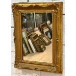 An Edwardian gilt composition rectangular rococo style wall mirror with later mirrored plate, (