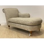 A modern floral upholstered chaise longue, raised on turned supports with brass cup castors,