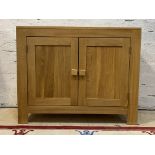 A modern light oak side cabinet, fitted with two panelled doors opening to a shelf behind, H77cm,