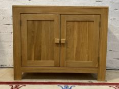 A modern light oak side cabinet, fitted with two panelled doors opening to a shelf behind, H77cm,