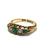 An 18ct gold three stone emerald and two stone diamond ring mounted in claw setting, the centre