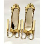 A pair of gilt wood wall appliques with shell shaped surmount and mirror panelled backs with twin