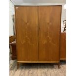 McIntosh, A mid century teak wardrobe, two doors enclosing two hanging rails, raised on square