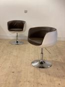 A pair of contemporary faux leather upholstered tub chairs, each raised on a rise and fall swivel