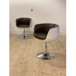 A pair of contemporary faux leather upholstered tub chairs, each raised on a rise and fall swivel