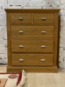 A modern light oak chest, fitted with two short and three long graduated drawers, raised on a