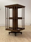 An Edwardian oak two tier revolving bookcase, with moulded slats, raised on cruciform base