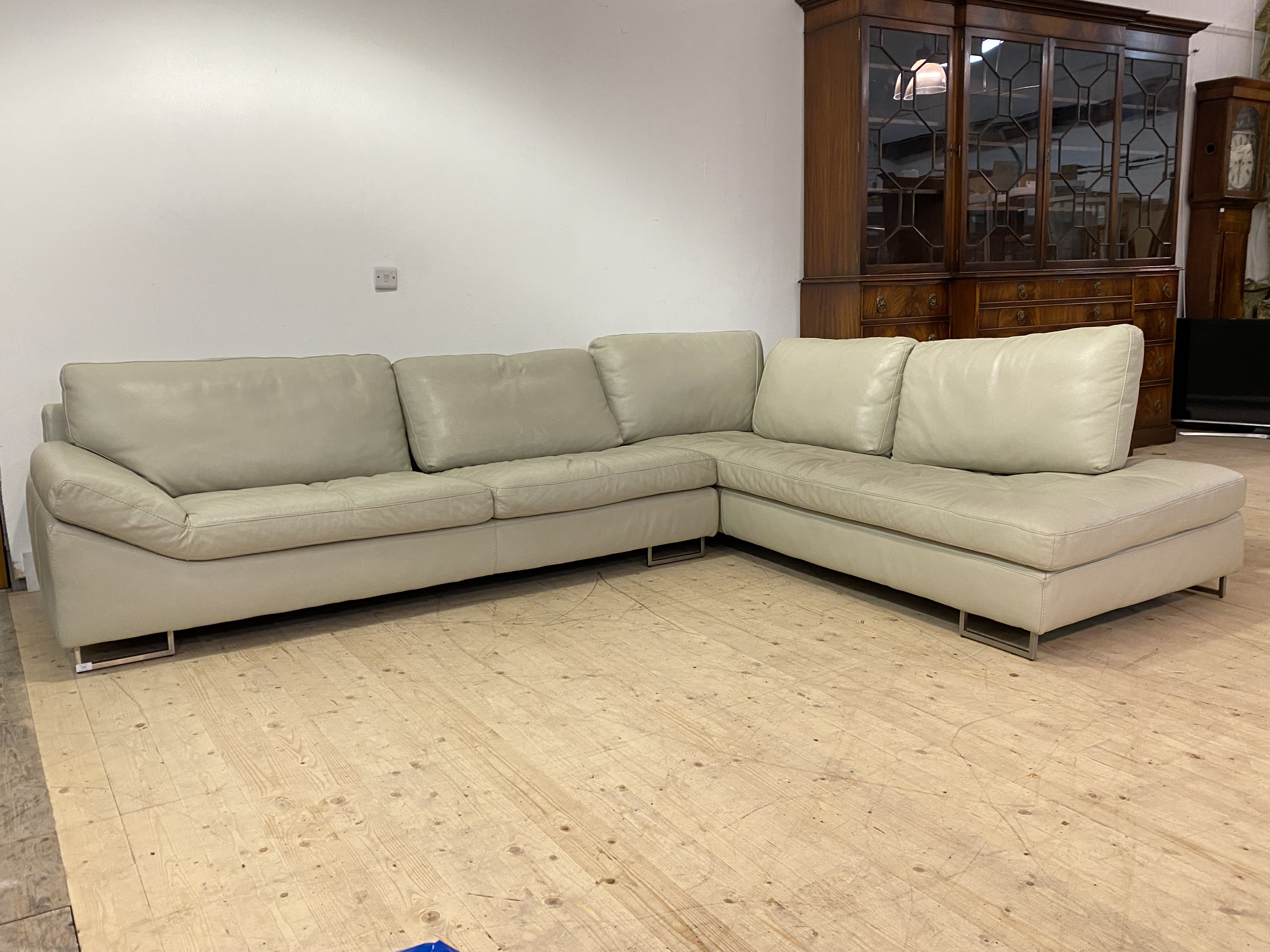 A Contemporary cream leather upholstered corner sofa, raised on brushed metal square section