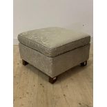 A modern floral upholstered ottoman footstool, with lift up top enclosing a storage well, raised