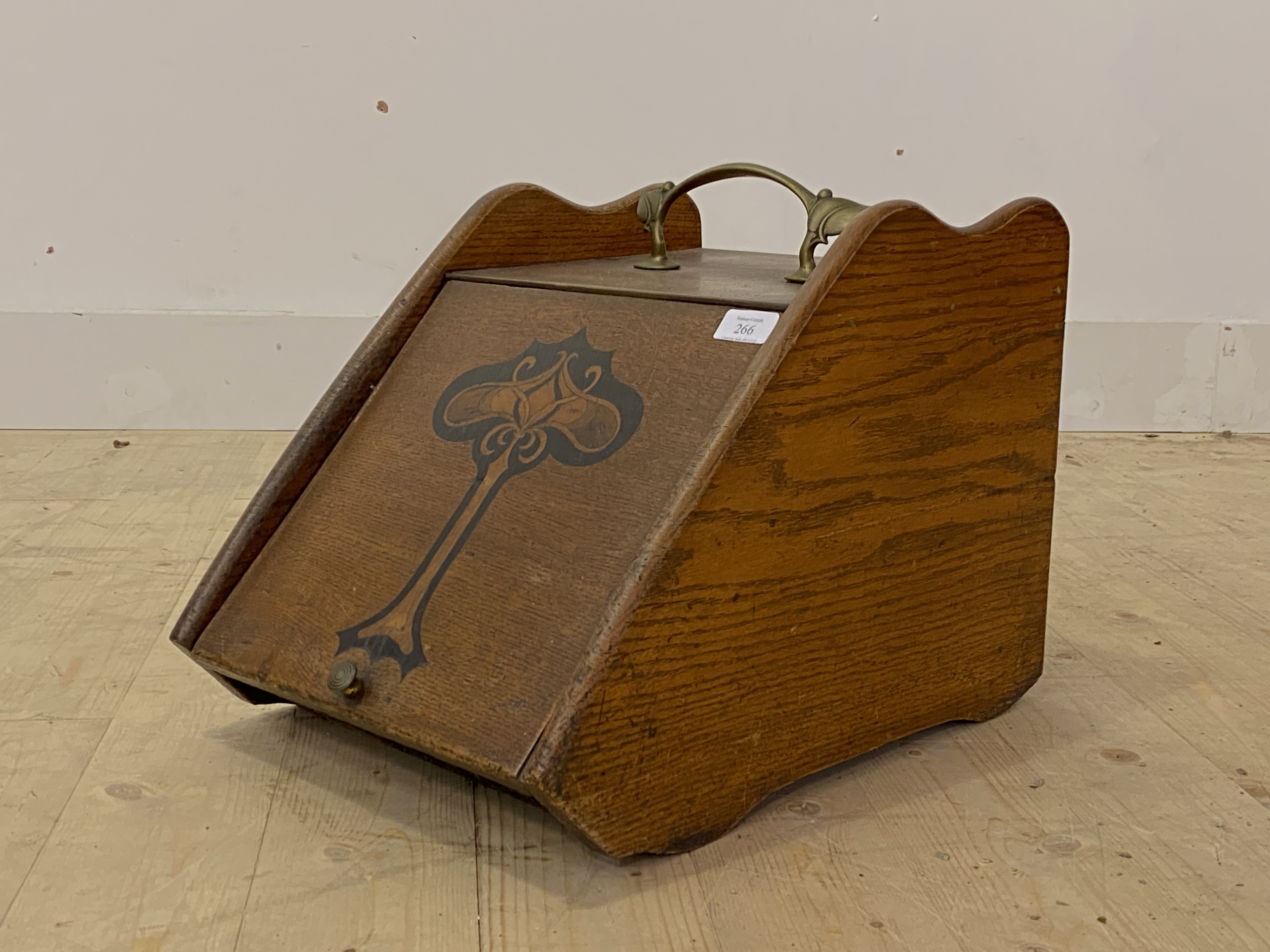 An Art Nouveau period oak coal box, with floral cast brass carry handle over sloped front with