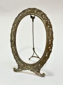 A white metal oval photograph frame raised on scroll end supports with easel stand, (internal