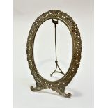 A white metal oval photograph frame raised on scroll end supports with easel stand, (internal