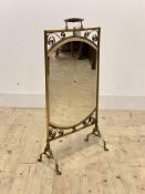 An Edwardian brass mirrored fire screen, with turned handle over scrolling decoration to frame
