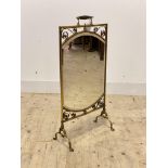 An Edwardian brass mirrored fire screen, with turned handle over scrolling decoration to frame