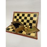 A folding vintage chess board and a collection of ebonised and ash carved chess pieces