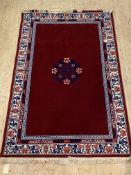 A Chinese washed wool rug, the red field with floral medallion and ivory border, 200cm x 310cm