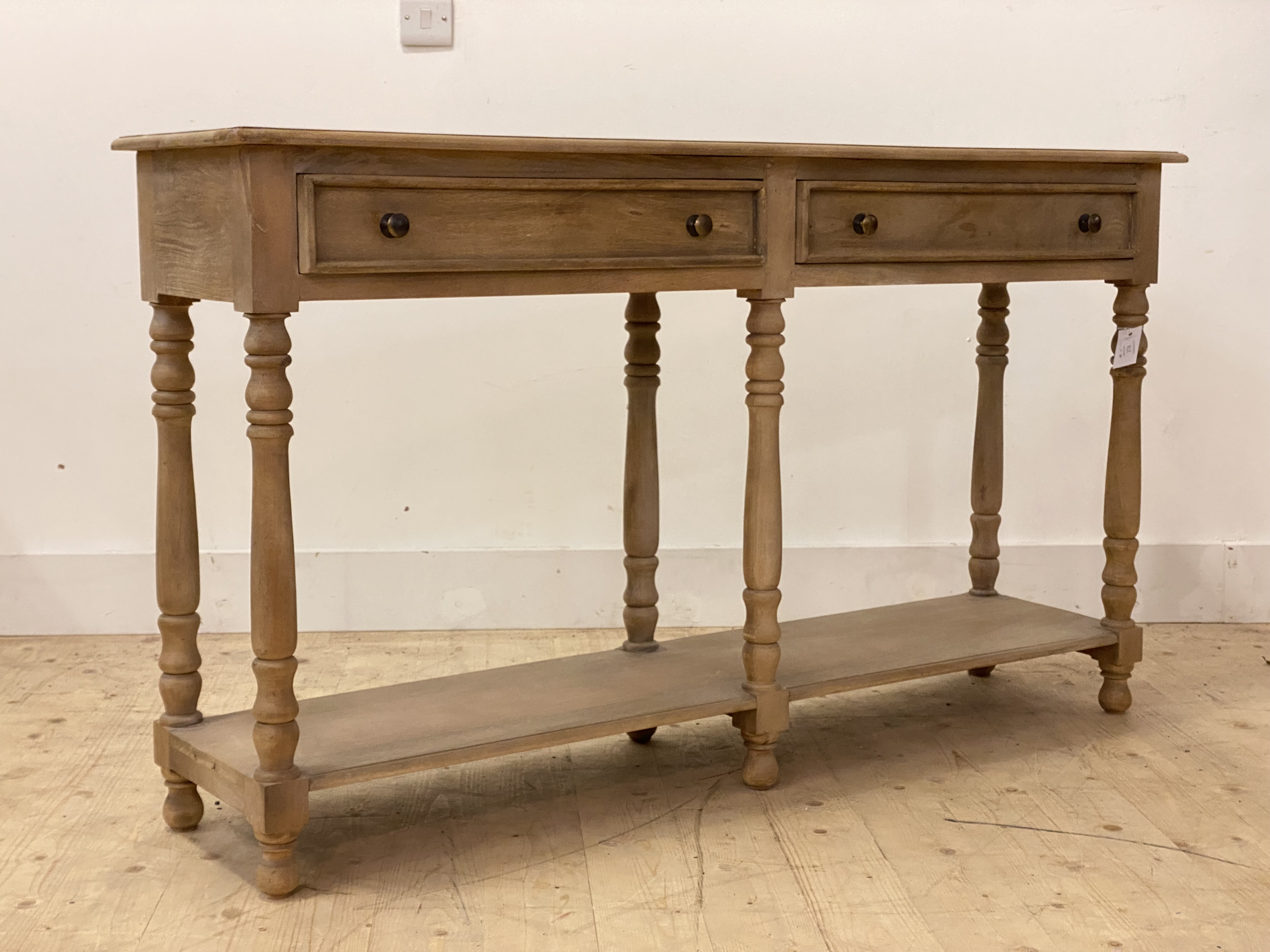An 18th century style bleached walnut dresser base, fitted with two drawers over turned supports