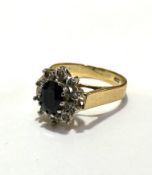 An 18ct gold sapphire and diamond cluster ring, the oval sapphire approximately .25ct, with a