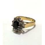 An 18ct gold sapphire and diamond cluster ring, the oval sapphire approximately .25ct, with a