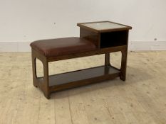 A mid century telephone table, with glass top and open shelf flanking a faux leather upholstered